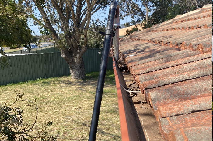 Photo of our gutter vacuum unit cleaning gutter, working at ground level as it moves along the gutter