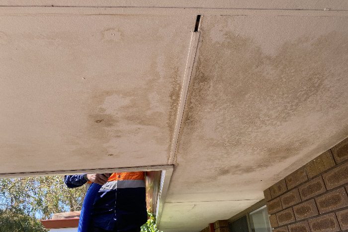 Photo under house eaves, showing large water stains from overflowing gutters